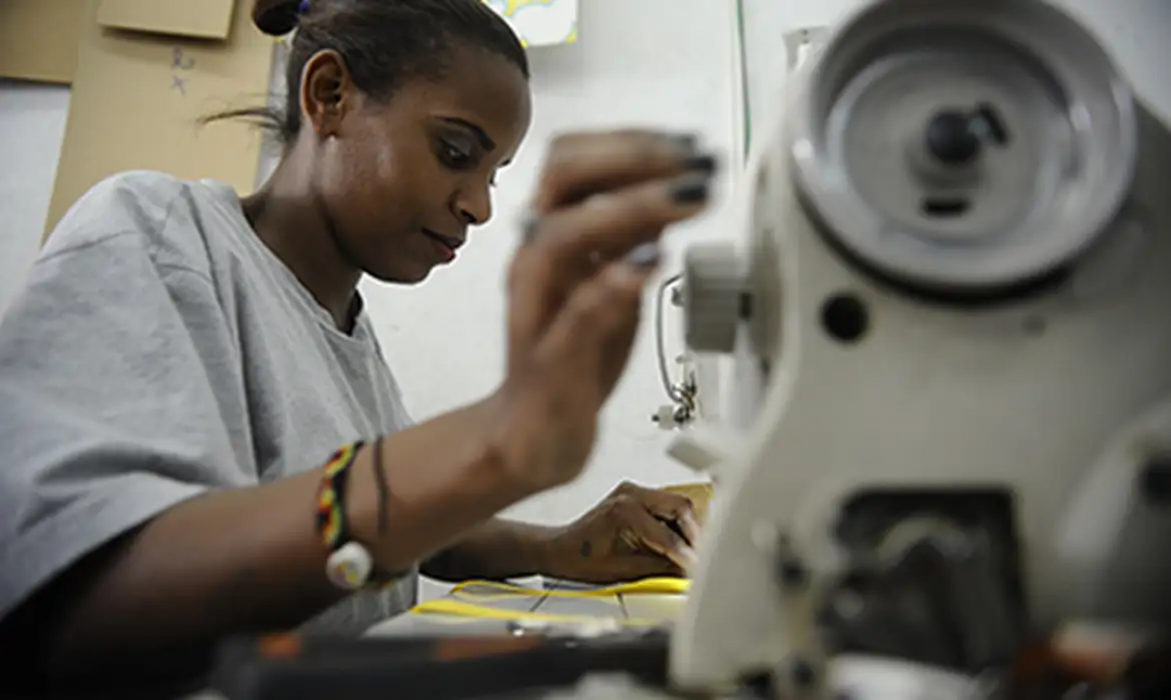 Mulher trabalha em máquina de costura